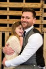 Ritratto di uomo barbuto che abbraccia la sua giovane figlia durante la cerimonia di nomina in un fienile storico. — Foto stock