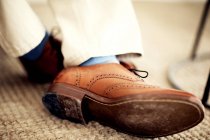 Close up of person feet, wearing brown leather brogues, blue socks and white trousers. — Stock Photo