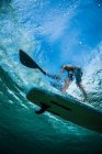 Disparo de una persona en un paddleboard tomado de debajo del agua. - foto de stock