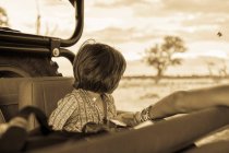 Un garçon de cinq ans en safari, dans un véhicule dans une réserve de chasse. — Photo de stock