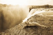 Молода дівчина у воді біля Диявольської пул спирається на лікоть, на краю скелі водоспаду Вікторія.. — стокове фото