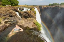 Young teenage girl in the water at the Devils Pool, on the cliff top overlooking Victoria Falls, Zambia, view from above. — Stock Photo