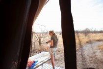 Двенадцатилетняя девочка, стоящая возле палатки в лагере дикой природы, используя свою камеру. — стоковое фото