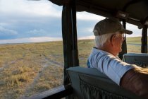 Senior man in safari vehicle, Kalahari Desert, Makgadikgadi Salt Pans, Botswana — Fotografia de Stock