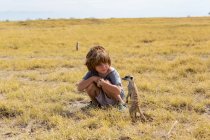 Niño de 5 años mirando Meerkats, desierto de Kalahari, sartenes Makgadikgadi, Botswana - foto de stock