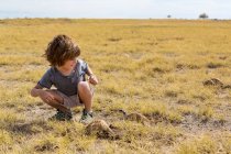 Niño de 5 años mirando Meerkats, desierto de Kalahari, sartenes Makgadikgadi, Botswana - foto de stock
