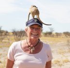 Sorrindo mulher sênior com Meerkat na cabeça, Kalahari Desert, Makgadikgadi Salt Pans, Botsuana — Fotografia de Stock
