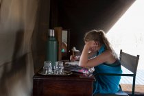 Дванадцятирічна дівчинка сиділа за столом у наметі в таборі заповідника дикої природи, малюючи . — стокове фото
