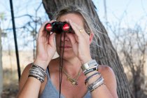 A woman using binoculars in a wildlife reserve camp. — Stock Photo