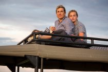 Mutter und Tochter im Teenageralter auf Safari-Fahrzeug und schauen in die Ferne. — Stockfoto