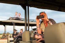 Donna anziana scattare foto con smart phone da una jeep safari. — Foto stock