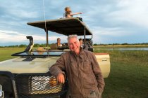 Un guide de safari souriant et une famille de touristes dans un véhicule de safari. — Photo de stock