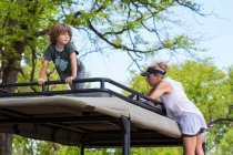 A five year old boy and mother on the observation platform of a safari vehicle under trees. — Stock Photo