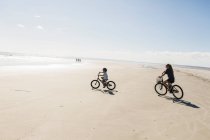 Двоє дітей катаються на велосипеді на відкритому пляжі, хлопчик і дівчинка . — стокове фото