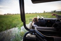 Um menino de seis anos de idade andando em veículo safari olhando para fora sobre a paisagem — Fotografia de Stock