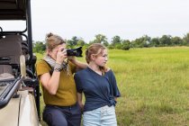 Madre che fotografa con figlia adolescente vicino al veicolo safari, Botswana — Foto stock