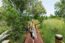Adult woman walking on wooden path, tented camp, Botswana — Stock Photo