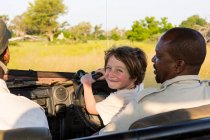 Sorridente 6 anni ragazzo sterzo safari veicolo, Botswana — Foto stock