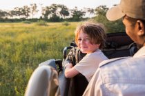 Sorrindo 6 anos de idade menino direção safari veículo, Botswana — Fotografia de Stock