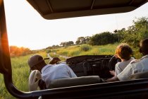 Ein sechsjähriger Junge am Steuer eines Safarifahrzeugs bei Sonnenuntergang, Botswana — Stockfoto