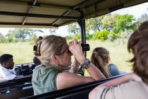Mulher adulta usando binóculos no veículo safari, Botsuana — Fotografia de Stock