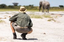 Führer kauert in der Nähe eines Elefanten in Nxai Pan, Botswana — Stockfoto