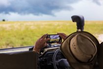 Guide Safari prenant une photo de téléphone intelligent des nuages orageux qui approchent. — Photo de stock