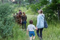 Un ragazzo e sua madre, turisti su un sentiero a piedi seguendo i membri del popolo San, boscaioli. — Foto stock