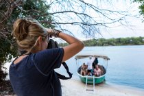 Una donna che usa la sua macchina fotografica, fotografa una barca con passeggeri sul fiume Zambesi, Botswana — Foto stock