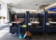 Zwei Kinder beobachten ihre digitalen Tablets und warten in einer Abflughalle des Flughafens auf einen Flug — Stockfoto