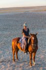 Una donna a cavallo al tramonto all'aperto. — Foto stock