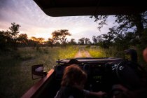 Motion blur, un véhicule safari conduisant sur une piste de terre avec phares allumés après le coucher du soleil. — Photo de stock