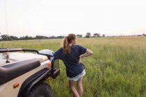 Ragazza di 13 anni appoggiata al veicolo safari, Botswana — Foto stock