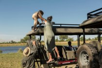 Mother and son climbing on on the observation platform of a safari vehicle — Stock Photo