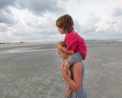 Frère de 5 ans chevauchant sur les épaules de sa sœur à la plage, Géorgie — Photo de stock