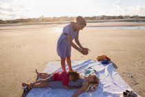 Мати смартфонізує своїх дітей на пляжі на заході сонця (Джорджія). — стокове фото