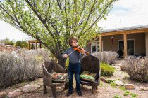 Garçon de 6 ans jouant du violon en dehors de sa maison — Photo de stock