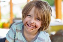Portrait of smiling 4 year old boy with chocolate on his face playing and laughing — Stock Photo