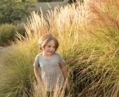 Garçon de 4 ans jouant dans l'herbe haute au coucher du soleil — Photo de stock