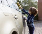4 year old boy washing a car in the parking lot — Stock Photo