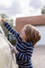 Четырехлетний мальчик моет машину на парковке — стоковое фото