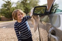 Quatro anos de idade menino polir um carro exterior com mais limpo e um pano — Fotografia de Stock