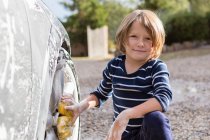 Garçon de quatre ans laver une voiture avec un nettoyant et un chiffon — Photo de stock