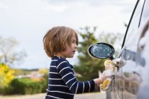 Vierjähriger Junge wäscht Auto mit Putzmittel und Tuch — Stockfoto