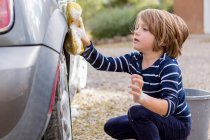 Vierjähriger Junge wäscht Auto mit Putzmittel und Tuch — Stockfoto