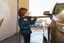Niño de 4 años lavando un coche en el lavado de coches - foto de stock