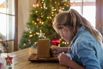 11 year old girl building a ginger bread house at home — Stock Photo