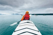 Une personne pagayant dans un kayak de mer double sur l'eau calme au large de la côte de l'Alaska. — Photo de stock