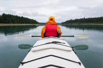 Woman sea kayaking calm water of an inlet in a national park. — Stock Photo