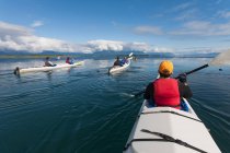 Un piccolo gruppo di persone kayak in acque incontaminate di una insenatura sulla costa dell'Alaska. — Foto stock